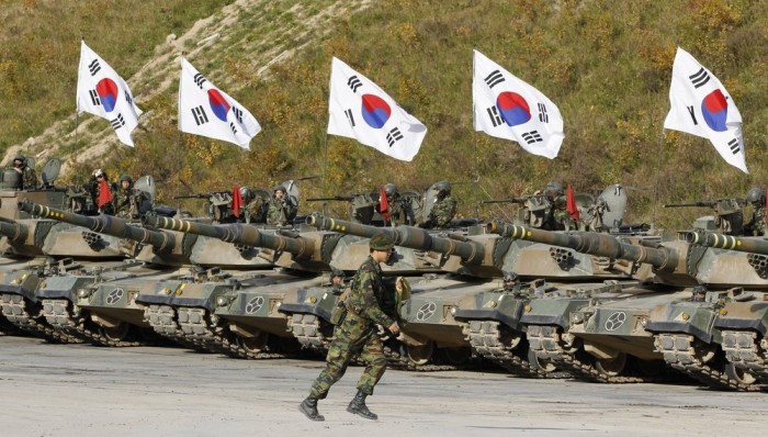 A South Korean army soldier runs in front of K-1 tanks after a live-fire military exercise as a part of the Seoul International Aerospace and Defense Exhibition 2011 on the Seungjin fire training field in Pocheon