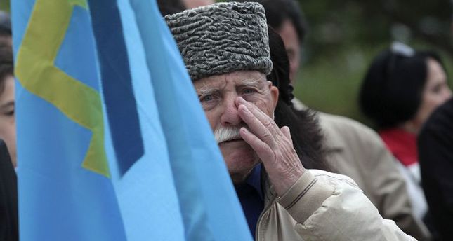 Crimean Tatar man holds flag during rally to commemorate mass deportations from region in 1944, in Crimean capital Simferopol