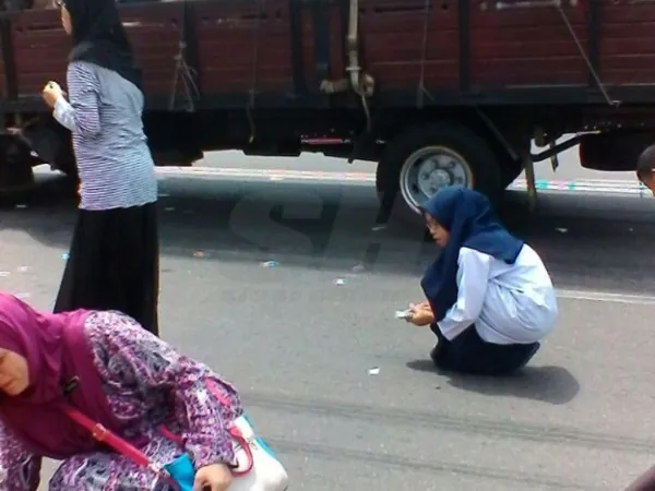Beberapa individu cuba mengutip cebisan dipercayai Al-Quran yang bertaburan di atas jalan. Foto -Sinar Harian